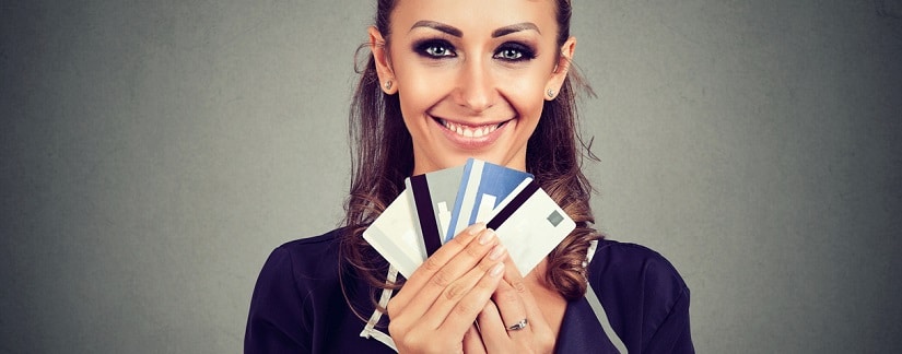 une jeune femme souriante tenant plusieurs cartes de crédit dans les mains