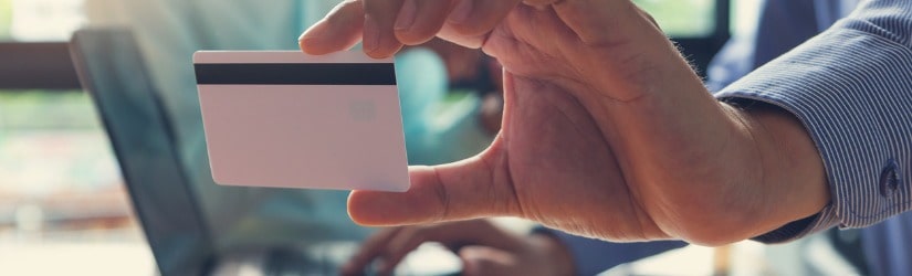 Homme d'affaires tenant une carte de crédit et utilisant un ordinateur portable pour faire des achats en ligne.