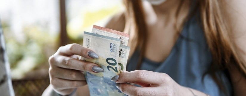 Une jeune femme masquée comptant le groupe de billets en euros.