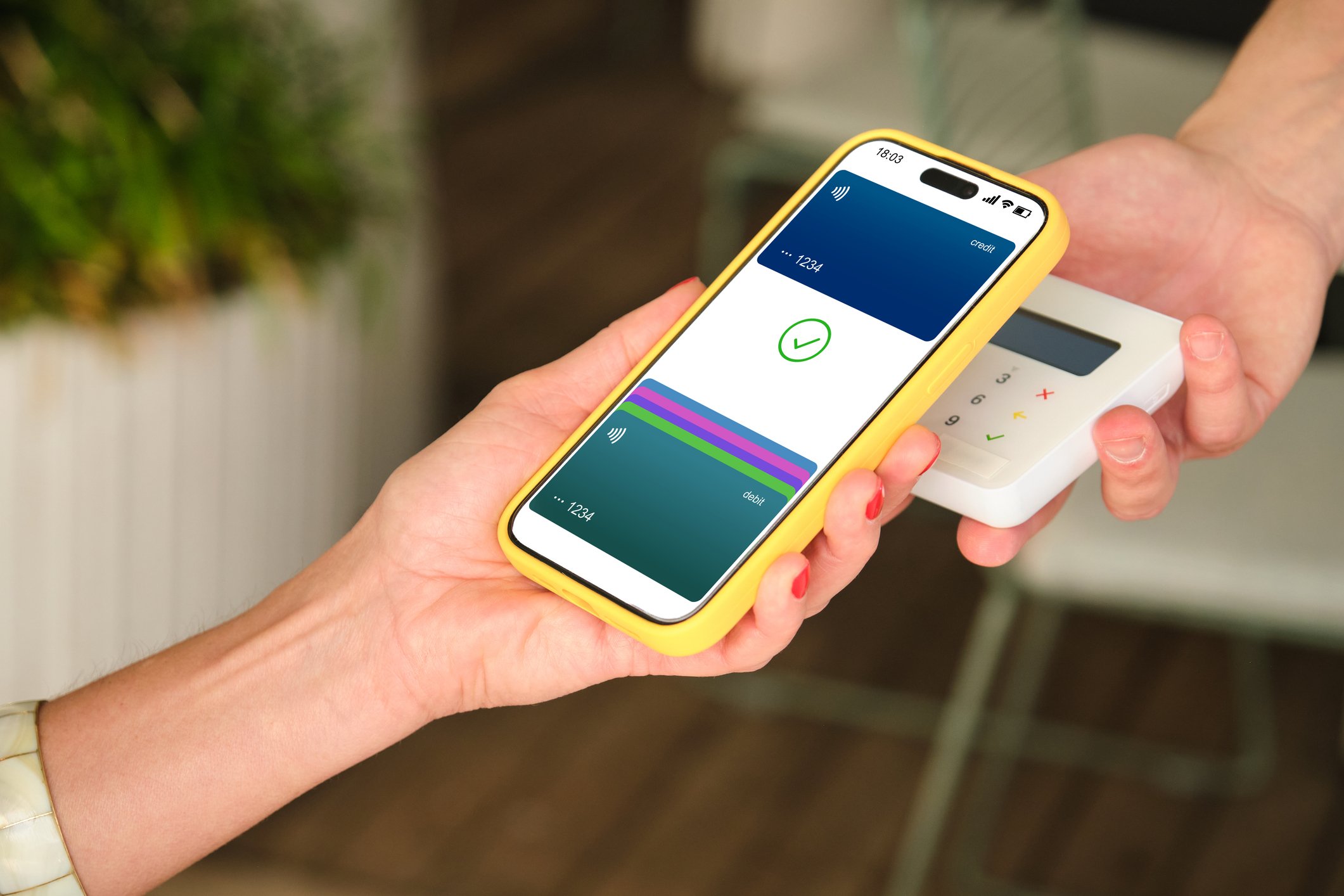 Gros plan sur des mains utilisant une application mobile et un terminal de paiement dans un café.