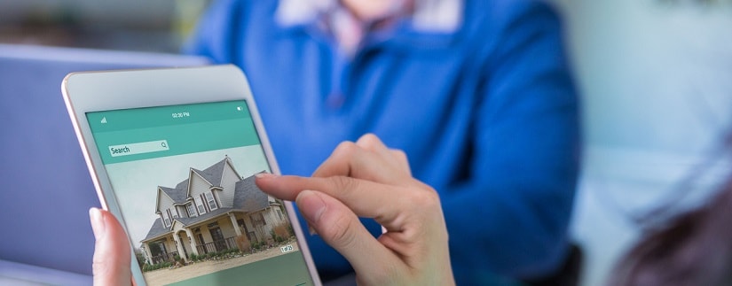Une femme utilise une tablette numérique pour acheter une maison.