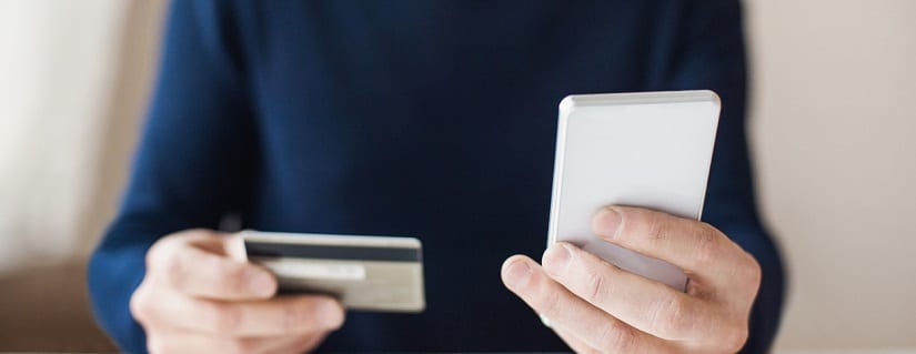 une personne tenant une carte de crédit et smartphone dans les mains