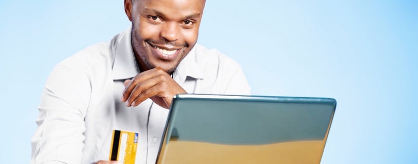 Un africain devant son ordinateur avec sa carte bancaire