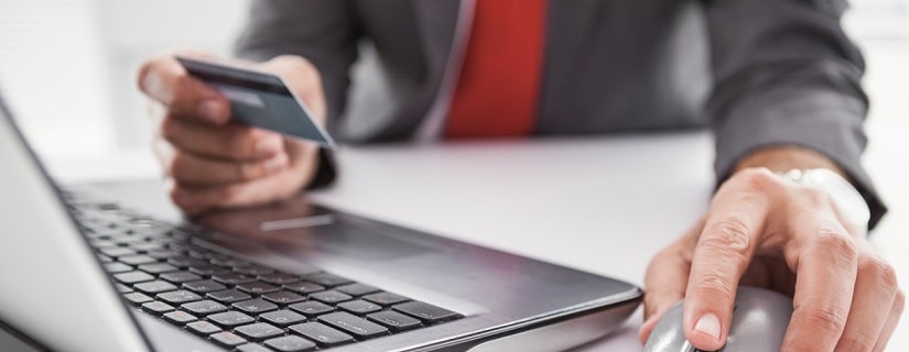 Un professionnel utilisant un laptop et tenant une carte de crédit dans la main