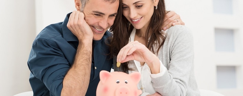 Un couple plaçant de la monnaie dans une tirelire en cochon