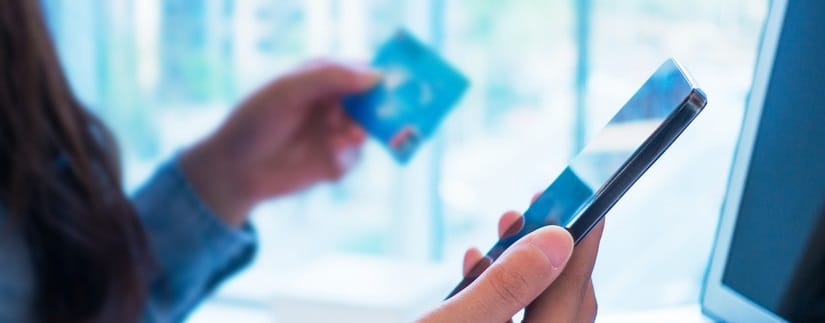 Une personne,carte de crédit à la main,en train d'effectuer une transaction via internet mobile