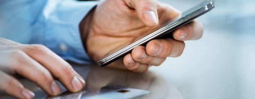 Une personne,carte de crédit à la main,en train d'effectuer une transaction via internet mobile