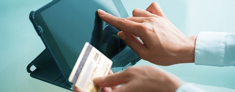 Une personne utilisant une tablette et tenant une carte de crédit à la main