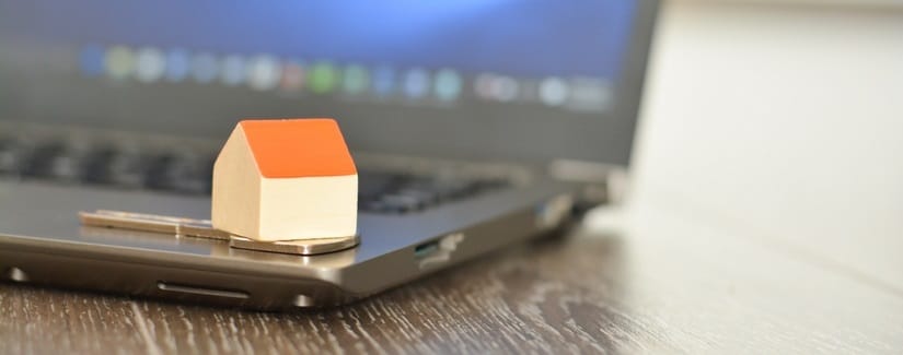 Une maison miniature placée sur un ordinateur portable