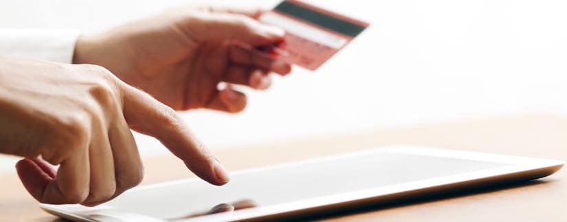 Une personne utilisant une tablette et tenant une carte de crédit à la main