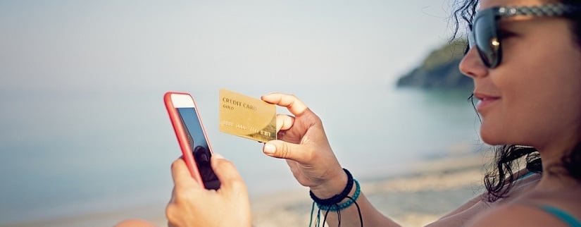 Une vacancière avec un smartphone et carte de crédit dans les mains