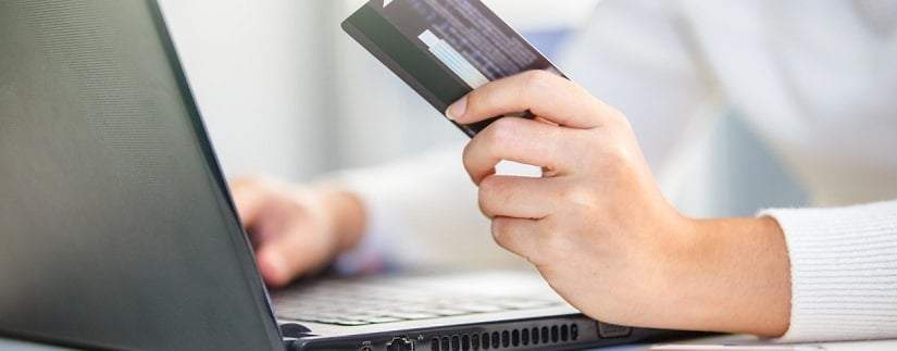 une personne,devant son laptop,tenant une carte de crédit