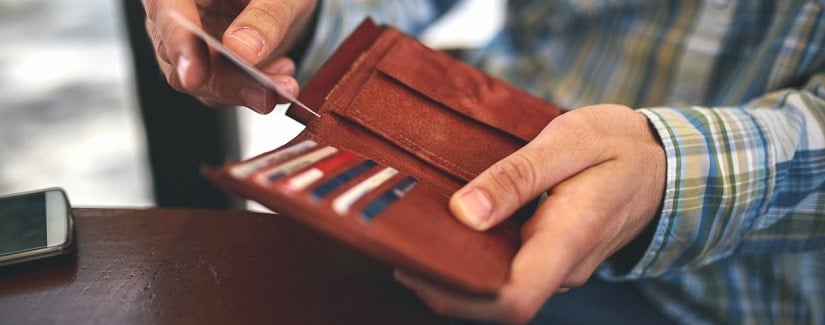 une personne sortant sa carte de crédit de son portefeuille