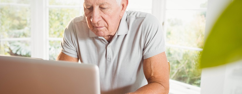 un retraité faisant des recherches devant son ordinateur