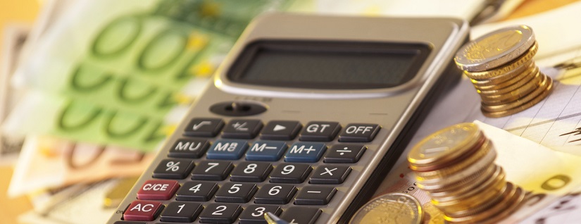 Une calculatrice avec des billets et des pièces de monnaies autour 
