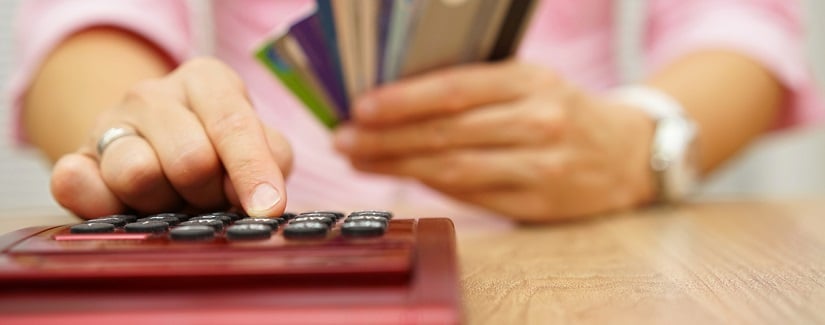 Une personne qui tient des cartes bancaires en utilisant une calculatrice