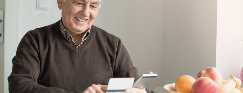 Un monsieur avec son smartphone tout en tenant sa carte bancaire 