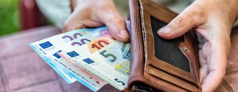 une femme rangeant ses billets euros dans son portefeuille