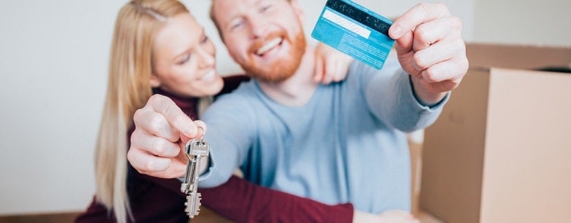 Un couple heureux tenant des clés ainsi qu'une carte bancaire 