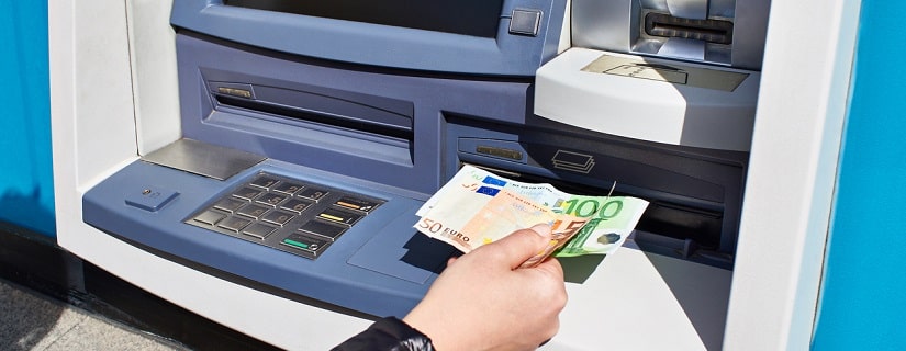 La main avec des billets en euros reçoit de l'argent d'un guichet automatique