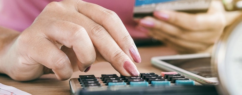 Une femme calculant ses dépenses à partir de cartes de crédit avec un téléphone intelligent sur le bureau