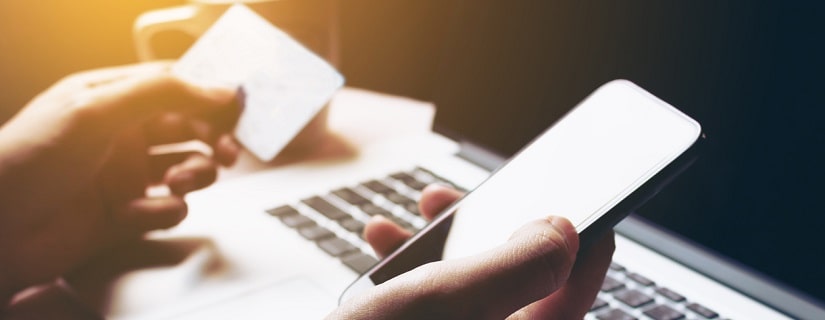 Une personne utilise une smartphone et un laptop pour se connecter à son compte bancaire en lingne.