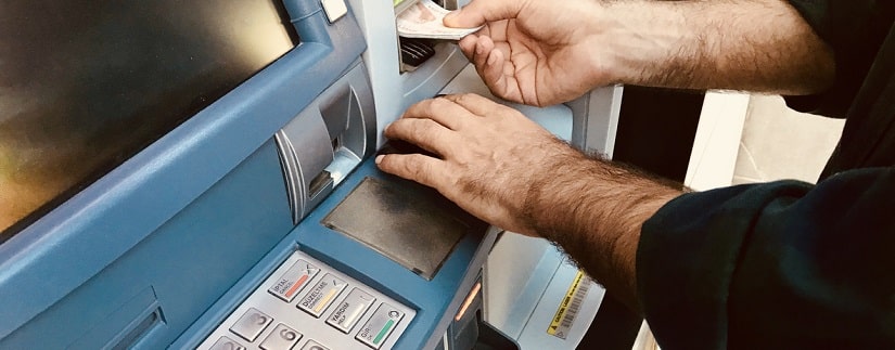 Un homme retire son argent sur le guichet automatique
