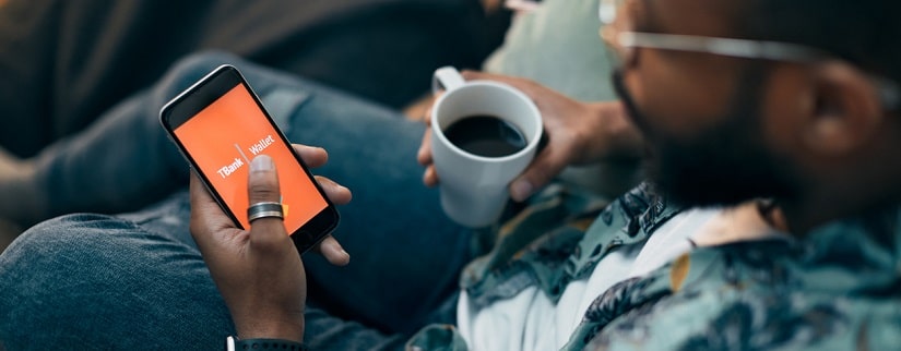 Un jeune africain tenant son téléphone pour faire visiter sa banque en ligne