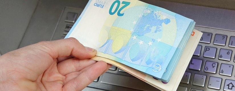 Une personne prend des billets en euros avec la main au guichet automatique