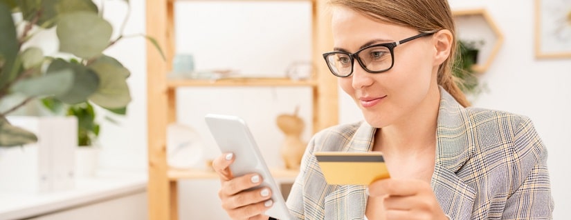 Jeune femme gestionnaire de bureau avec smartphone entrant les données personnelles de la carte de crédit par lieu de travail à la pause.