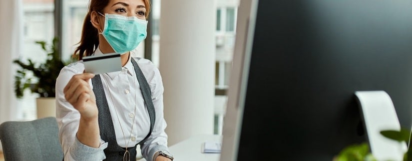 Une femme masquée avec une carte de crédit