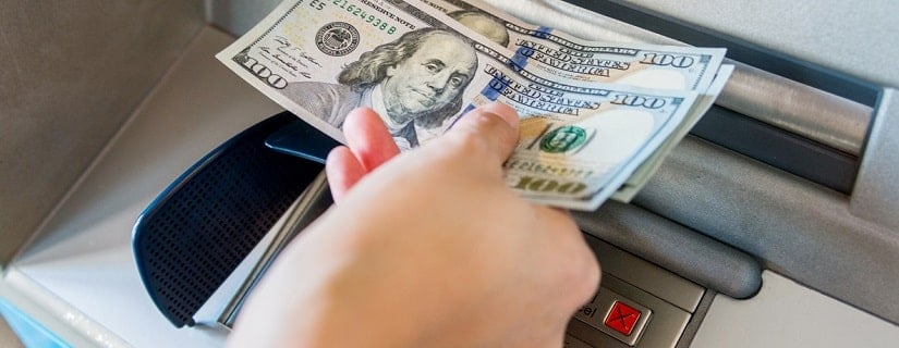 Main d’une personne prenant  son argent sur le guichet automatique.