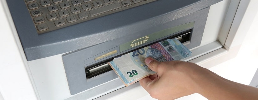 Retirer de l'argent à un guichet automatique avec des billets en euros.