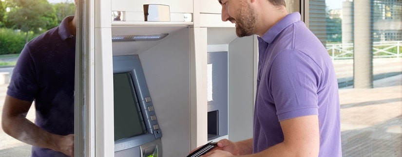 Homme à l'aide de sa carte de crédit dans un guichet automatique pour le retrait d'espèces.