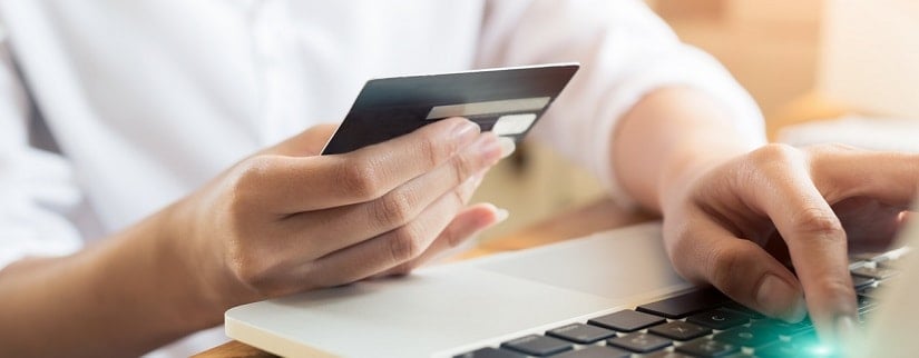 Une jeune femme tenant en mains une carte de crédit pour les achats en ligne à la maison.