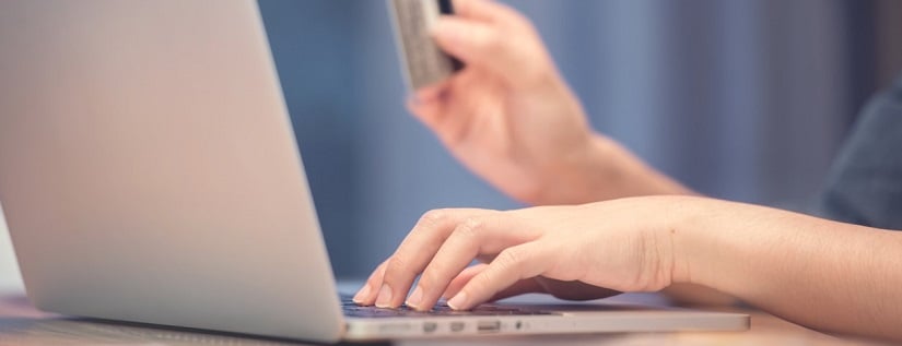 Mains de femme tenant une carte de crédit lors de l'utilisation d'un ordinateur portable. Concept d'achat en ligne.