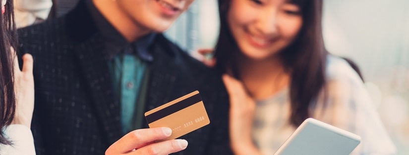 Jeune couple japonais fait des achats en ligne avec une tablette et une carte de crédit