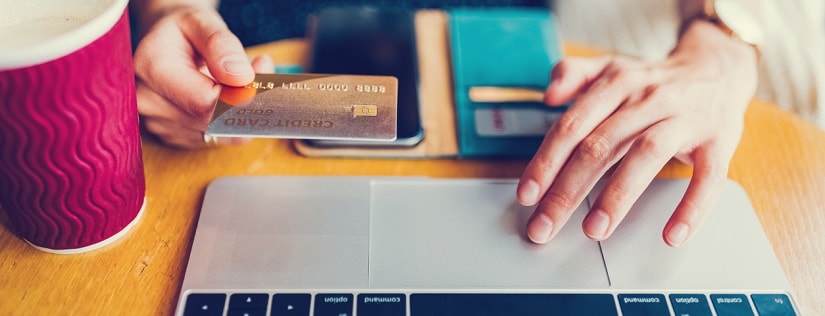 Une femme devant un laptop tenant une carte de crédit 