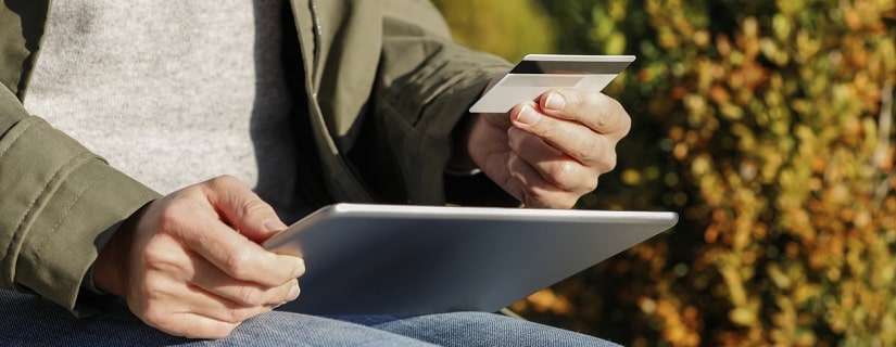 Une personne achète sur internet et paie avec une carte de crédit sans numéraire sur sa tablette à l'extérieur.