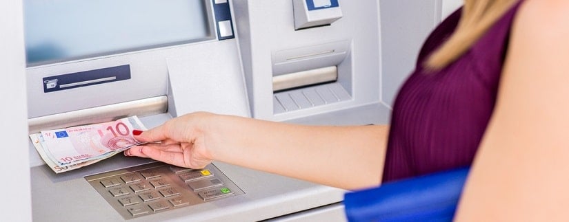 Une femme retirant de l'argent sur le distributeur automatique de billets.