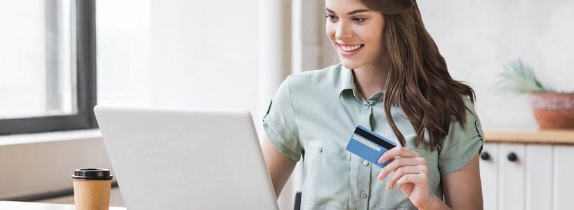 Belle jeune fille fait de l’achat en ligne via une carte de crédit et un laptop