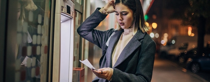 Jeune femme utilisant un guichet automatique pour retirer de l’argent dans la ville la nuit