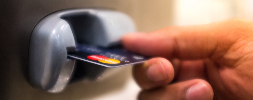 Homme insérant une carte de crédit bancaire dans un téléphone public.