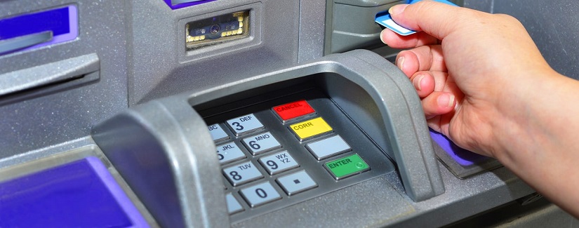 Femme utilisant sa carte de crédit sur un guichet automatique.