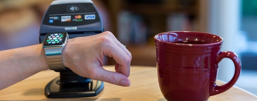 Une personne paie au comptoir d’un café en utilisant l’Apple Watch et un lecteur électronique.