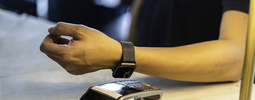 Client asiatique payant la facture à l’aide d’une smartwatch.