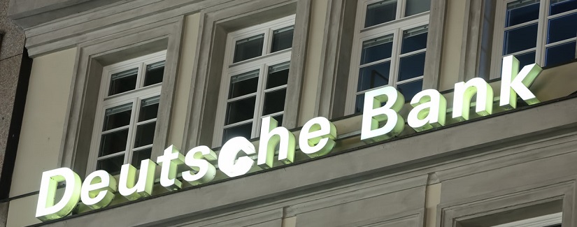 Gros plan du logo de la Deutsche Bank sur un bâtiment la nuit à Munich, en Allemagne.