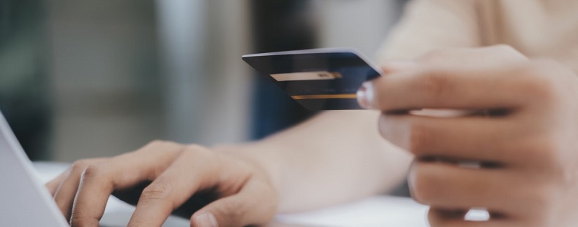 Fermer les mains en tenant la carte de crédit et en utilisant l’ordinateur portable et les achats en ligne.