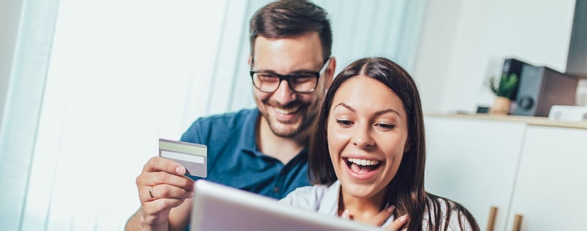 Couple heureux souriant avec ordinateur tablette et carte de crédit ou de banque shopping en ligne à la maison.