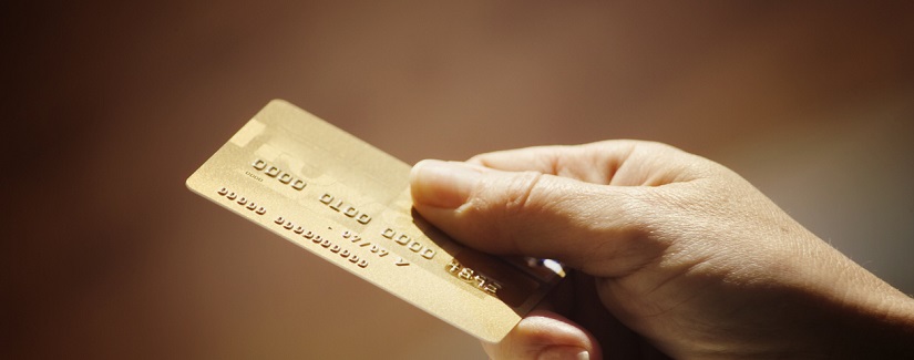 Main d’une personne tenant une carte de crédit en or.